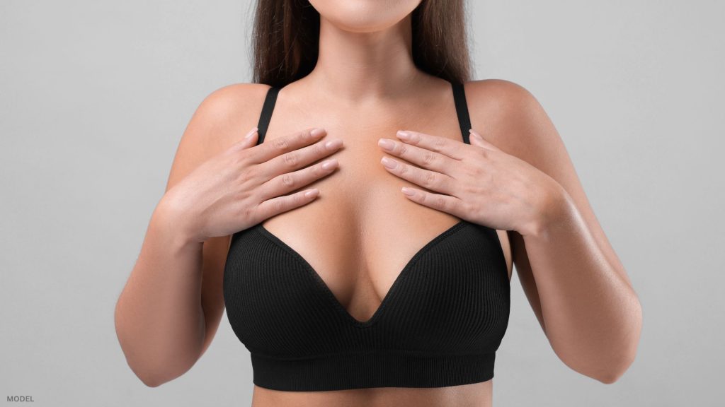 Woman in black bra touching chest (model)